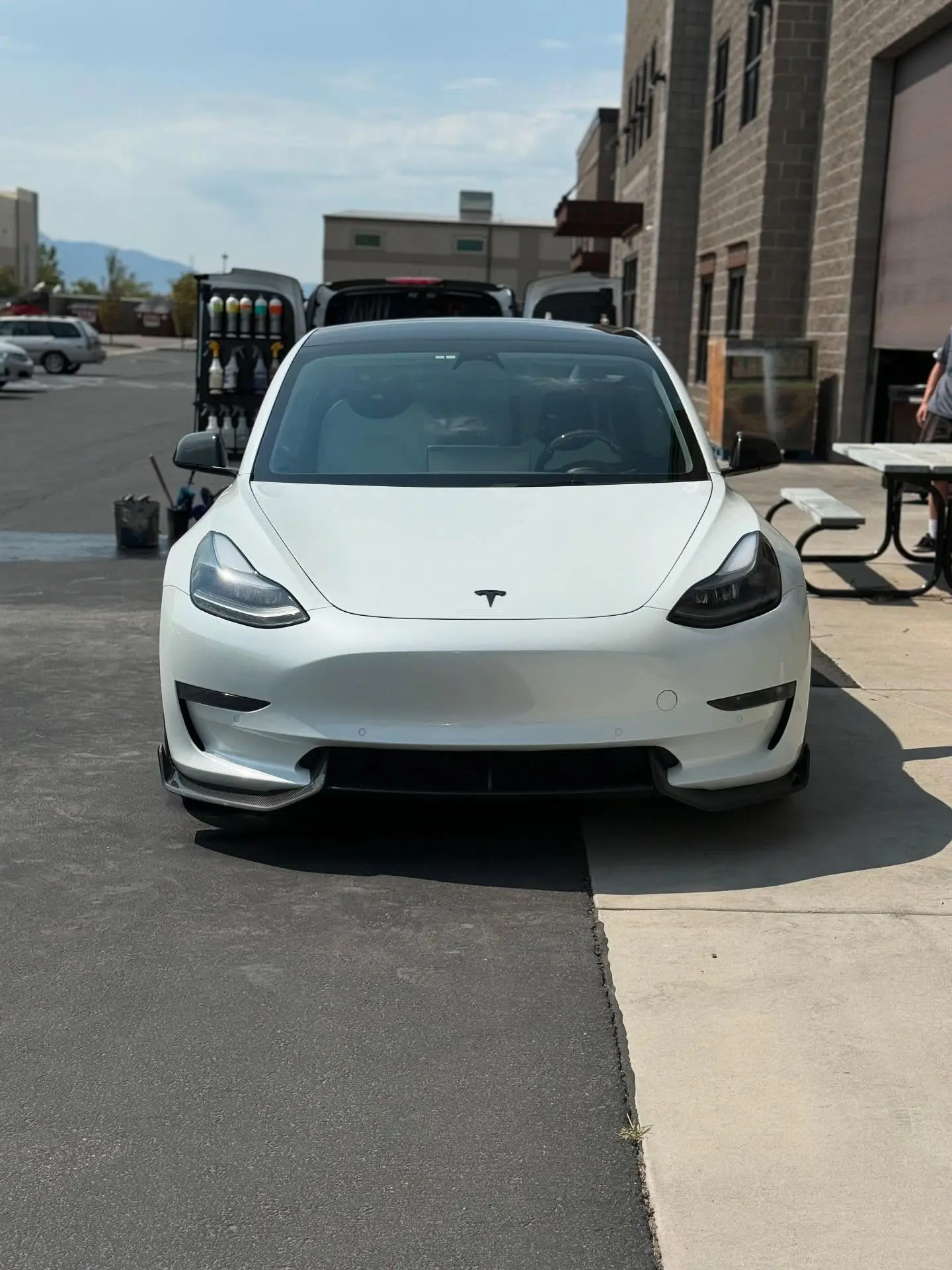 A white Tesla Model 3 parked outside the shop before detailing