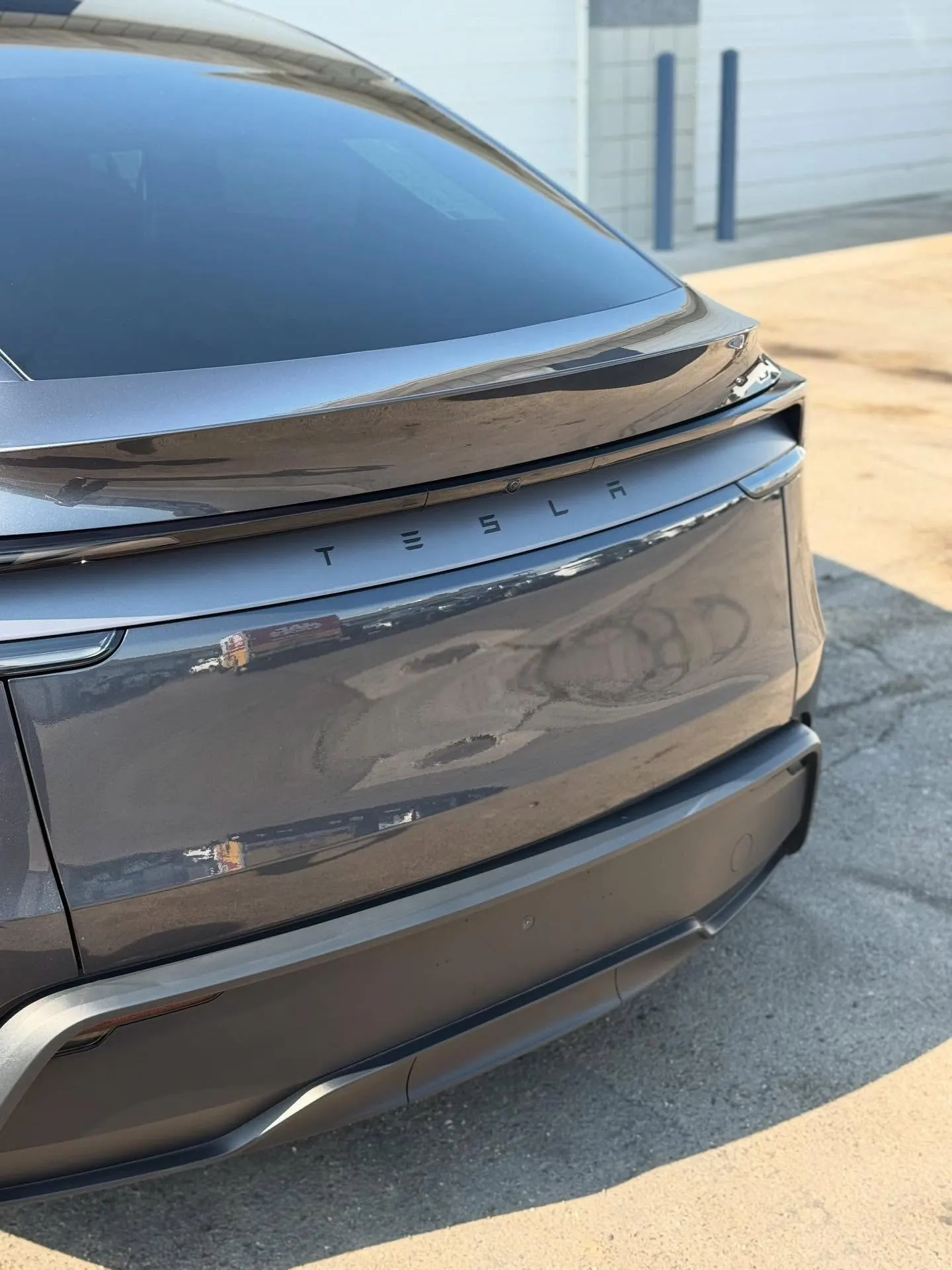The rear of a gray Tesla Model Y, paint deep and glossy