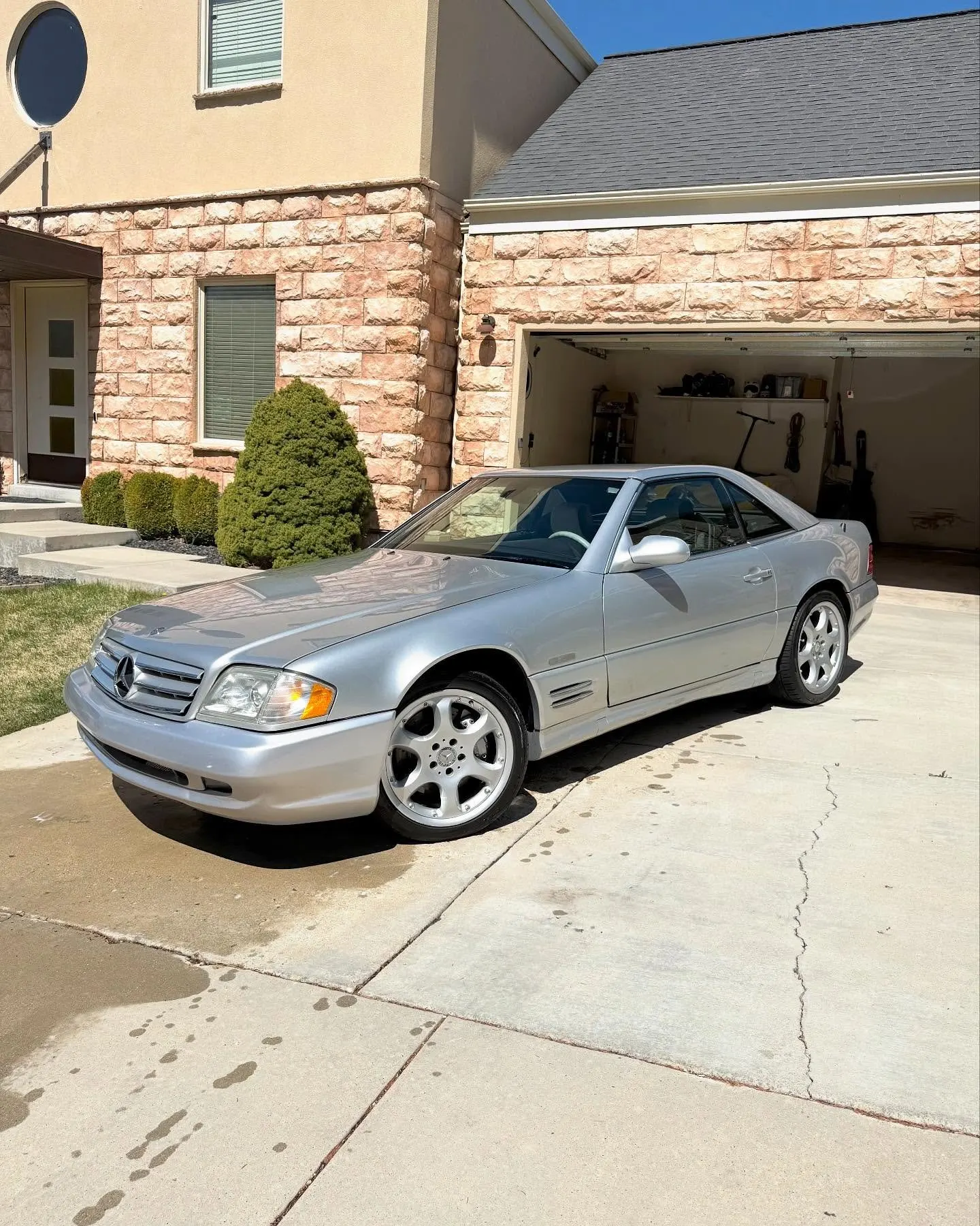 A silver Mercedes SL500 from the front three-quarter in a driveway